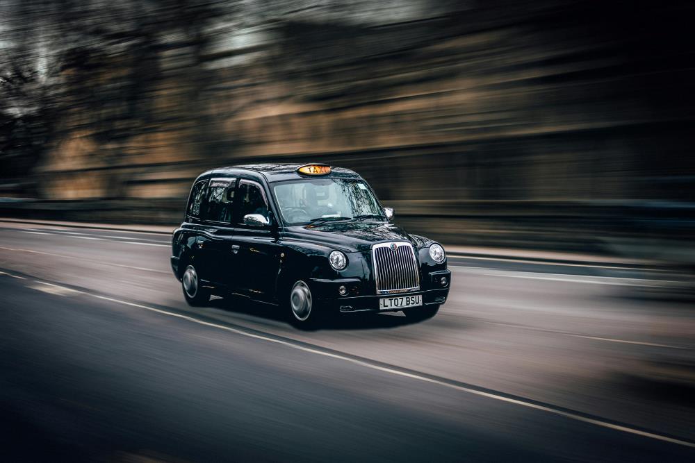 A picture of a London taxi driving down a road