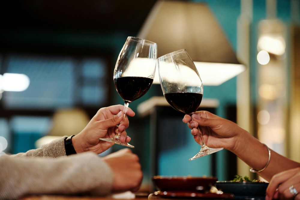 Close-up of Man and Woman Clinking Glasses with Red Wine
